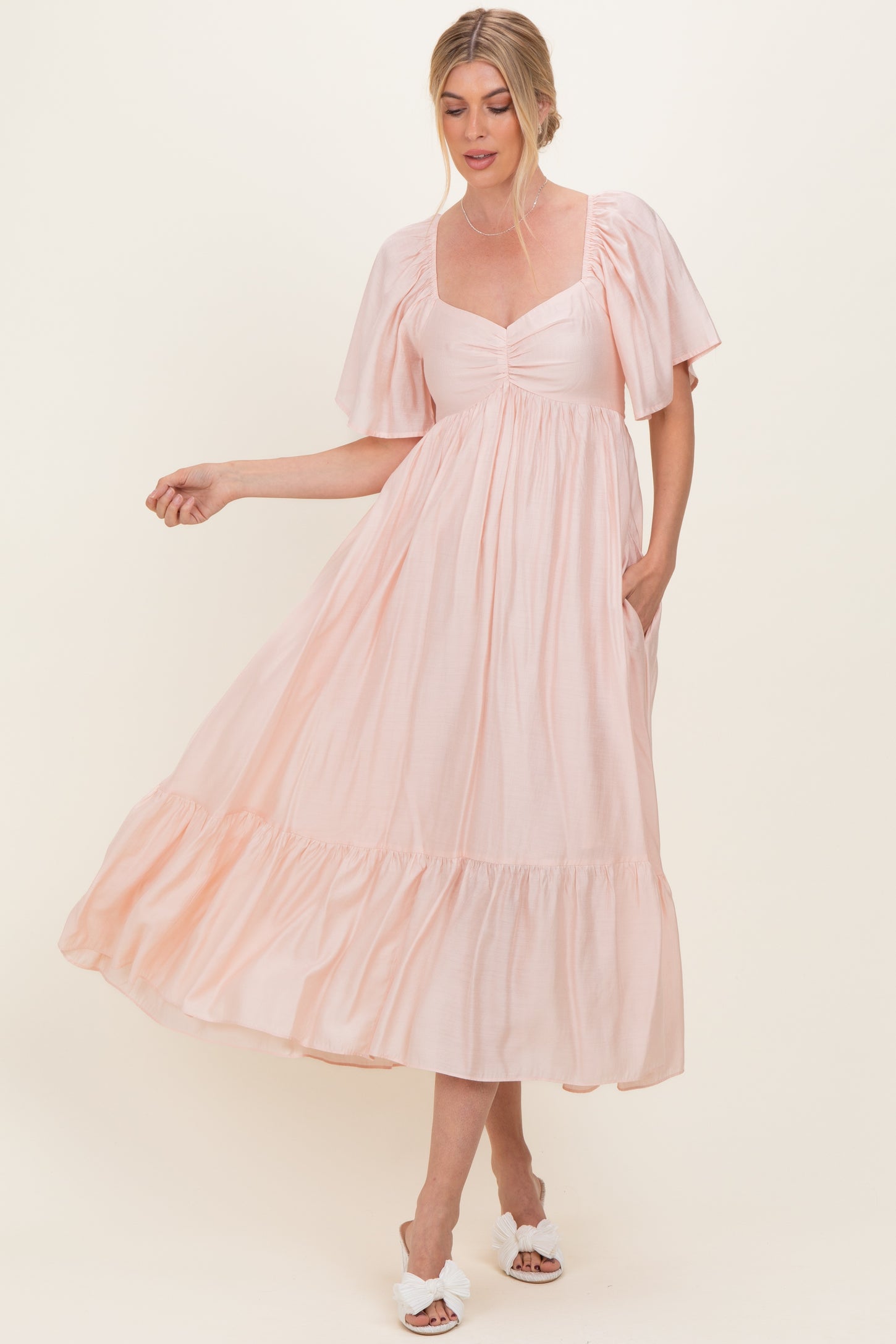 woman wearing a light pink puff sleeve maxi dress with gathered bodice and tiered hem