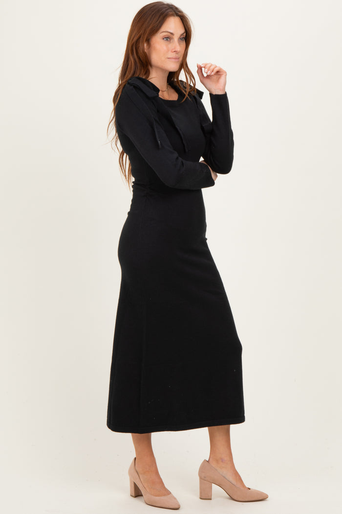 woman wearing a black long sleeve maxi dress with a fitted silhouette and a hood, paired with nude block heel shoes