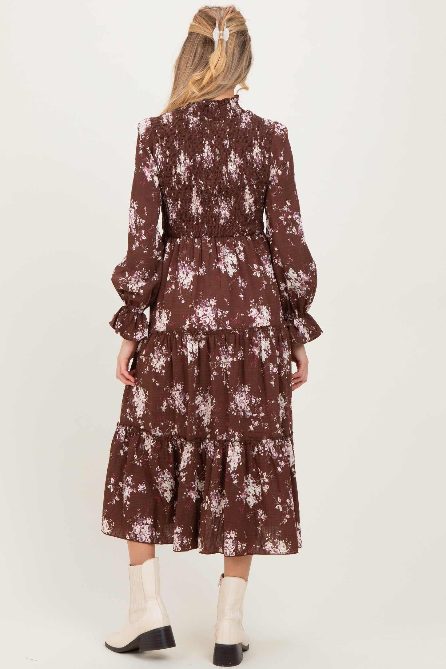 woman wearing a brown floral maternity dress with tiered design and long sleeves, viewed from the back