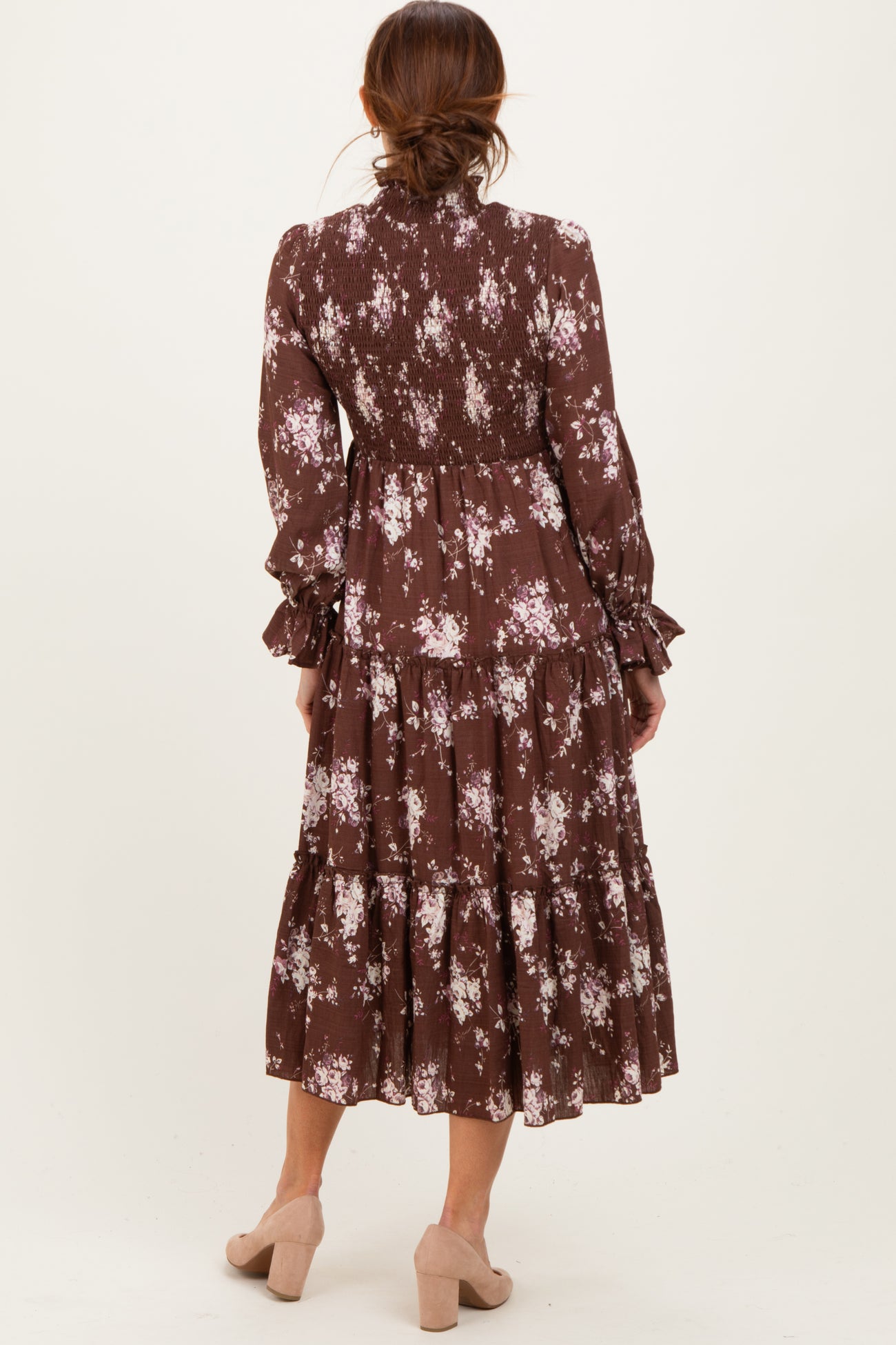 woman wearing a brown floral tiered midi dress with long sleeves and smocked details, seen from the back