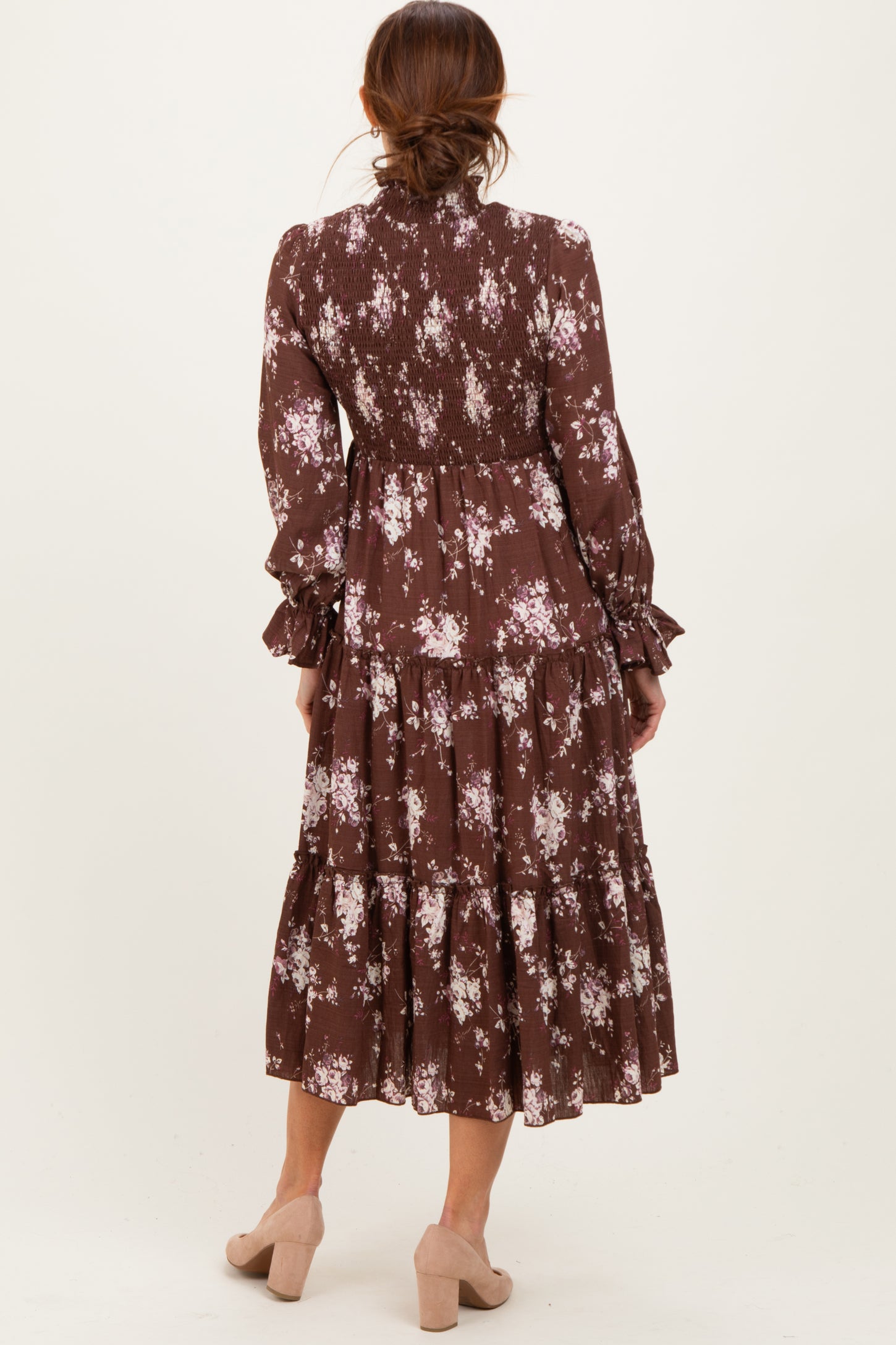 woman wearing a brown floral tiered midi dress with long sleeves and smocked details, seen from the back