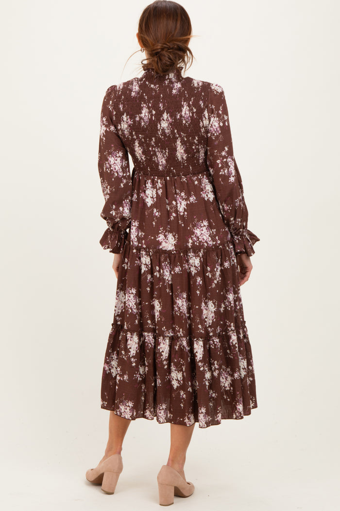 woman wearing a brown floral tiered midi dress with long sleeves and smocked details, seen from the back
