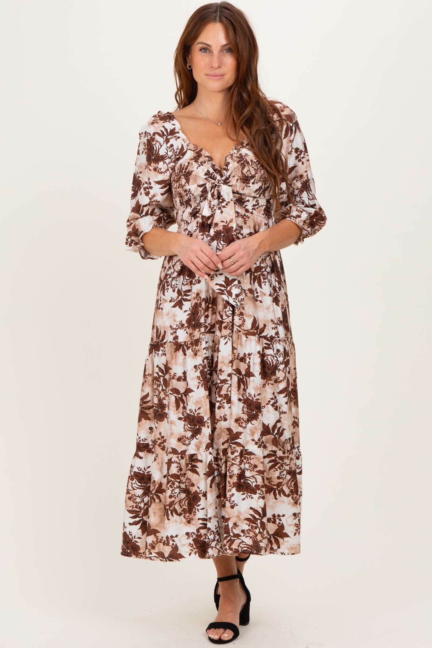 woman wearing a brown and white floral maxi dress with puff sleeves and a tiered skirt
