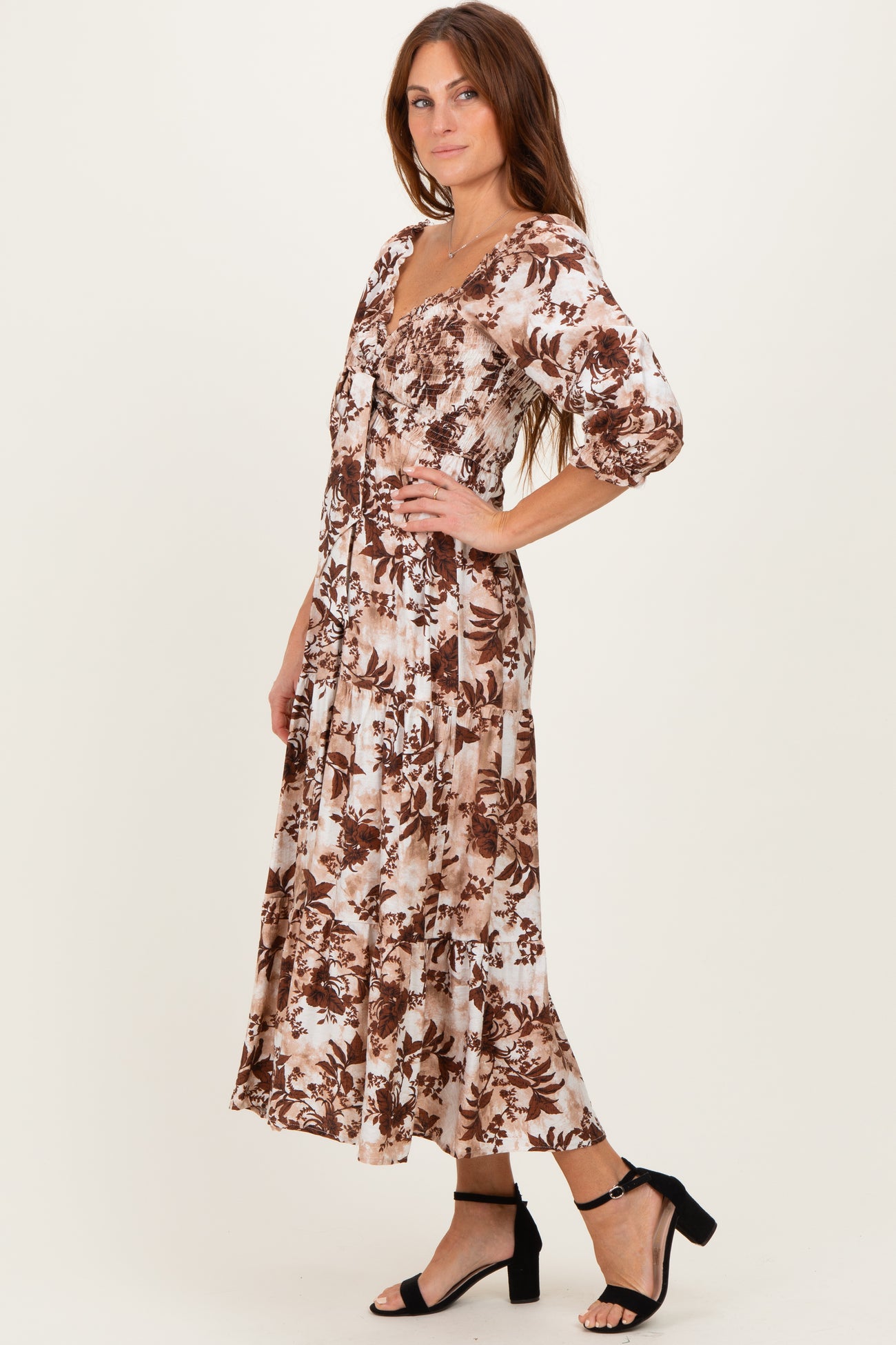 woman wearing a brown and cream floral midi dress with three-quarter sleeves and a fitted bodice