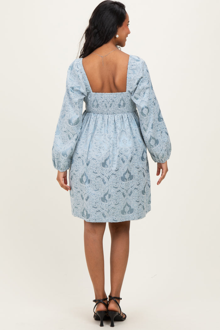 woman wearing a light blue maternity dress with puff sleeves and a smocked back, showing off a baby bump