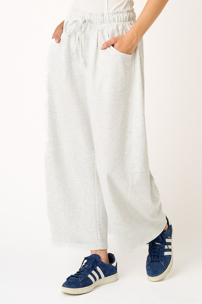 woman wearing light gray wide-leg joggers with an elastic waistband and side pockets, paired with blue sneakers