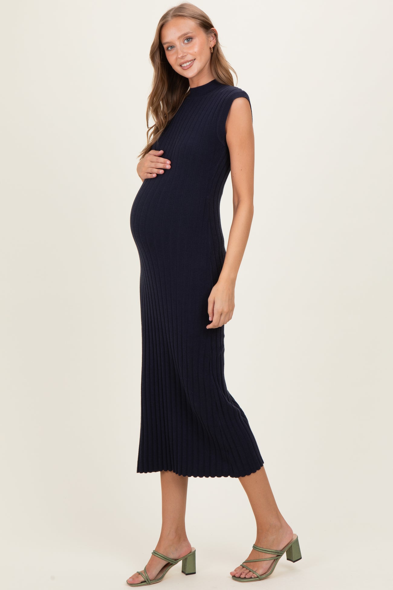 woman wearing a navy ribbed maternity dress and holding her baby bump