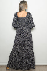 woman wearing a long black floral maxi dress with puffed sleeves and a square back view