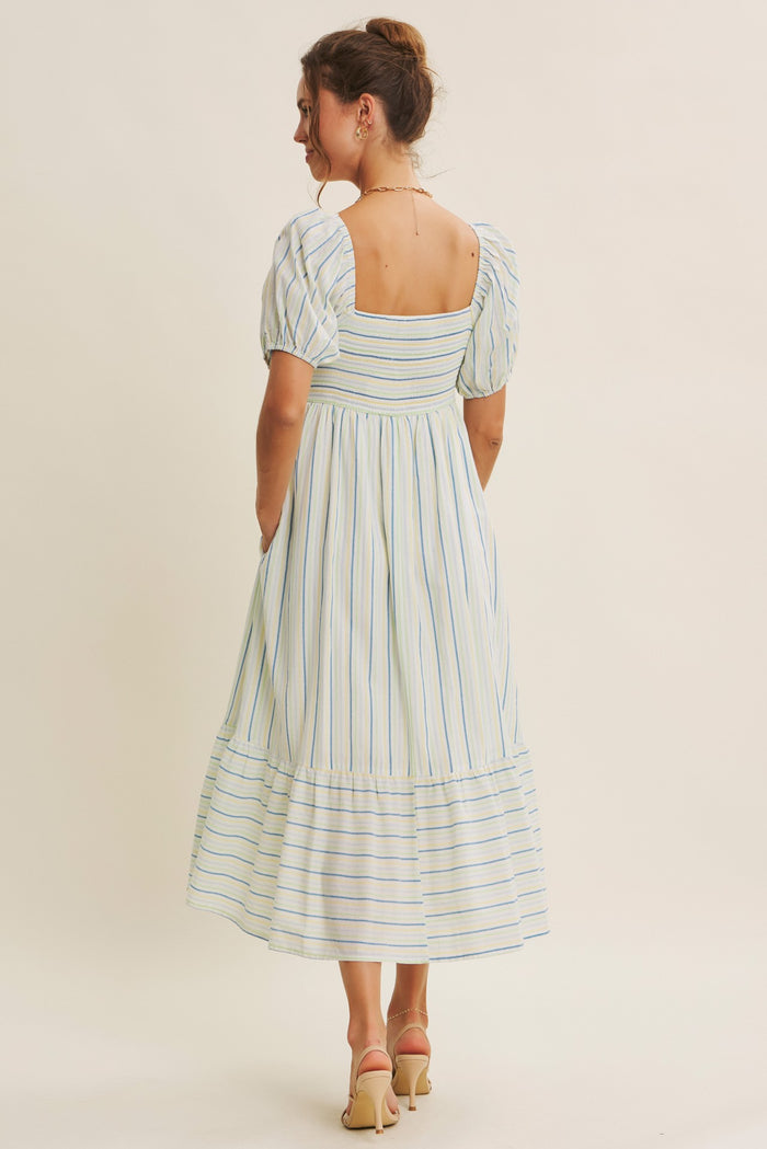 woman wearing a light blue striped puff-sleeve midi dress with a square back and tiered hemline