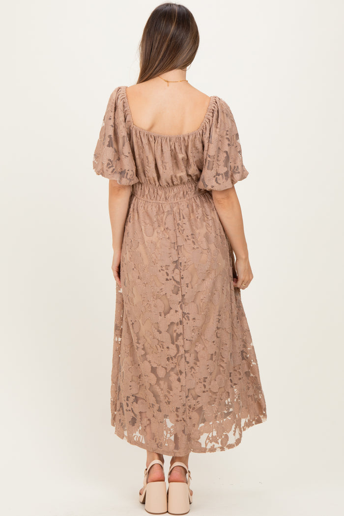woman wearing a dusty rose maternity dress with puff sleeves and a gathered waist, showing an elegant lace design