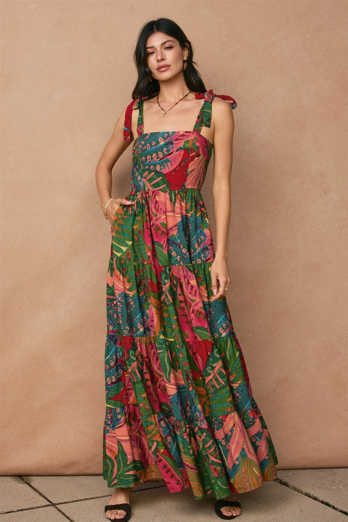 woman wearing a colorful floral maxi dress with tie straps and a tiered skirt