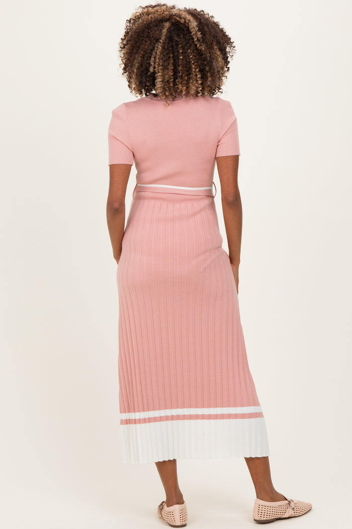 woman wearing a light pink ribbed maternity dress with short sleeves and a white striped hem