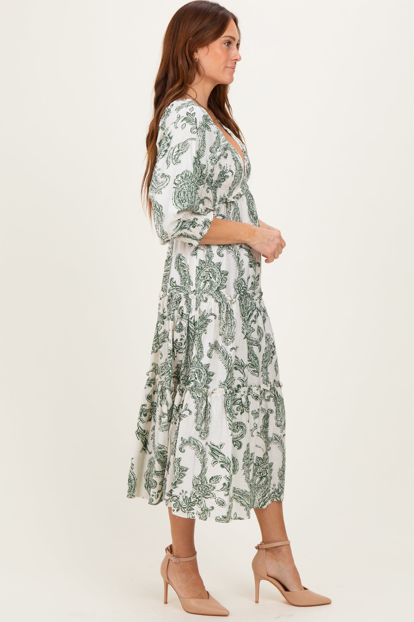 woman wearing a white and green floral print midi dress with three-quarter sleeves and a flowy skirt