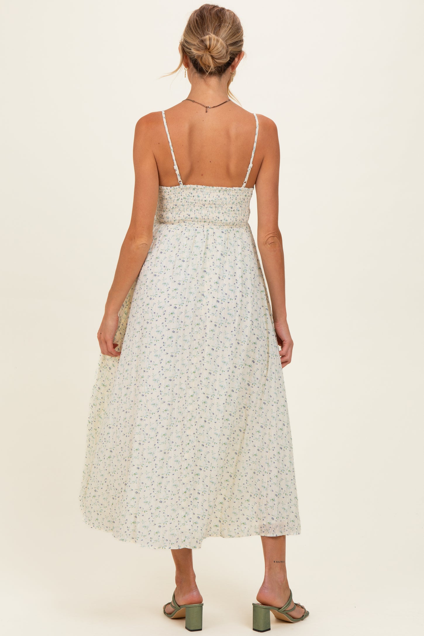 woman wearing a floral print maternity maxi dress with adjustable straps, showing a fitted bodice and flowing skirt