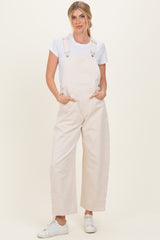 woman wearing a white t-shirt and light beige overalls with wide legs and pockets, styled with white sneakers
