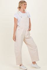 woman wearing beige wide-leg overalls with side pockets and a white t-shirt, styled with white sneakers