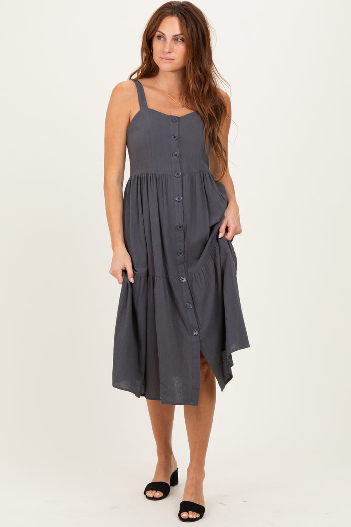 woman wearing a gray button-down midi dress with adjustable straps and a tiered skirt, posing with one hand on the fabric