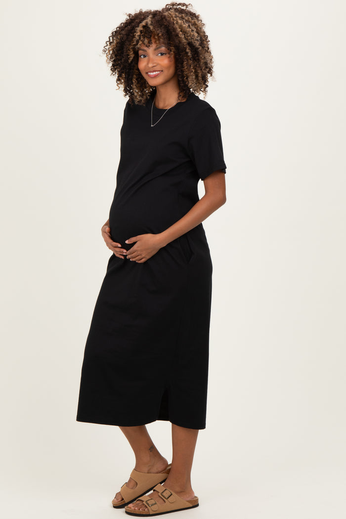 woman wearing a black maternity dress with short sleeves and side pockets, showcasing her baby bump
