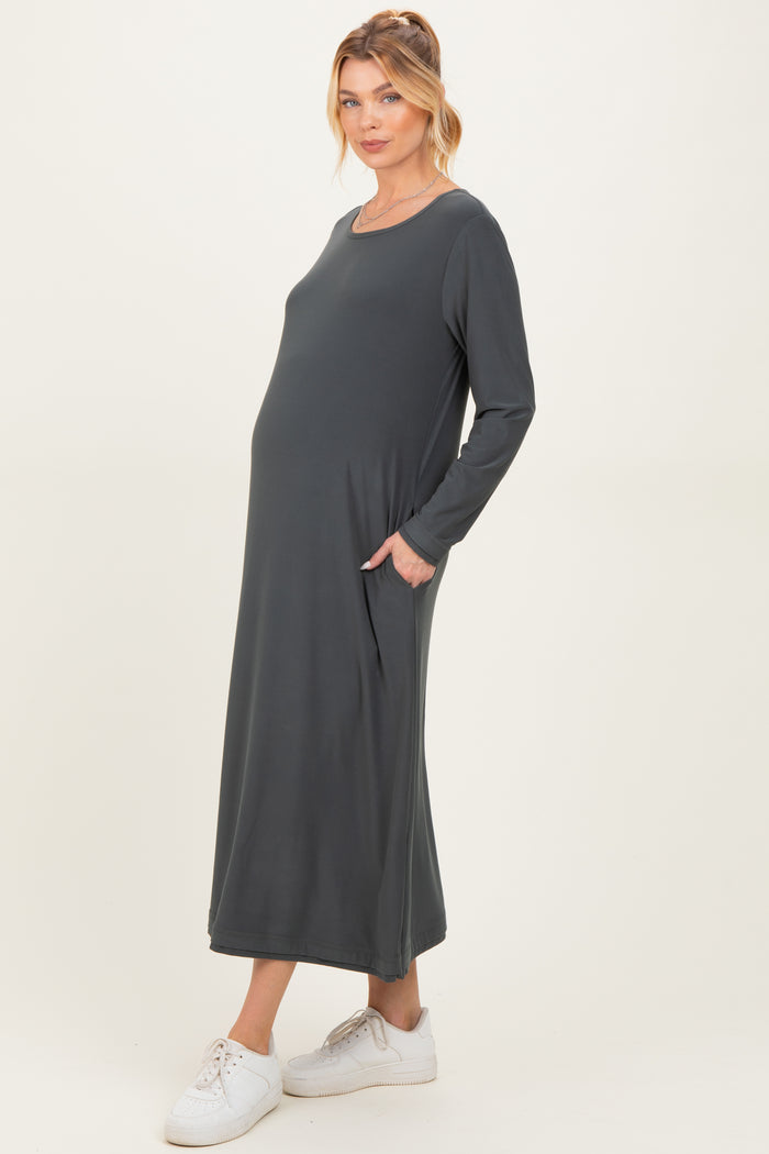 woman wearing a dark gray long sleeve maternity dress with pockets and a visible baby bump