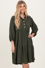 woman wearing a dark green tiered shirtdress with button details and puff sleeves