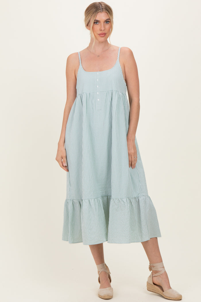 woman wearing a green and white gingham midi dress with adjustable straps and a ruffled hem
