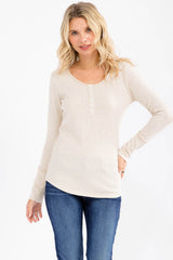 woman wearing a light beige long sleeve henley top with button details and a rounded hem, paired with blue jeans