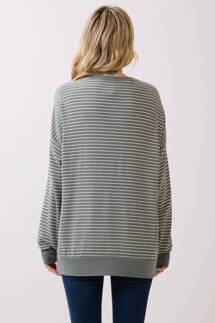 woman wearing a gray and white striped oversized sweatshirt, viewed from the back, paired with dark blue jeans