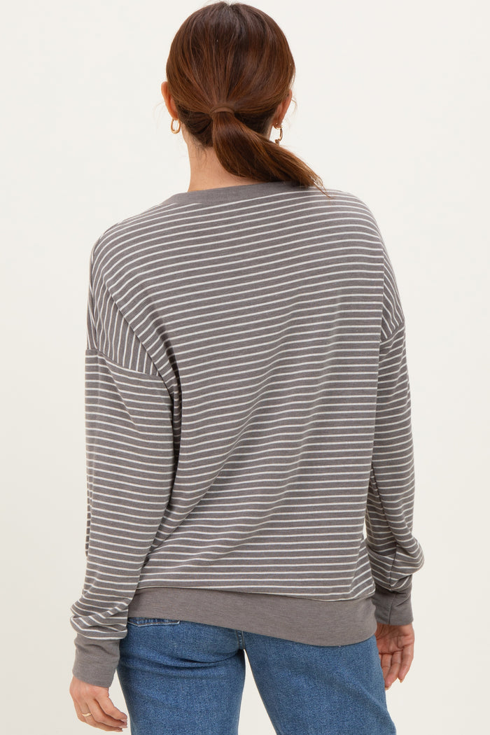 woman wearing a gray and white striped long sleeve oversized sweatshirt, viewed from the back