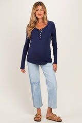 woman wearing a navy blue long sleeve maternity top with buttons and distressed light blue jeans, showing her baby bump