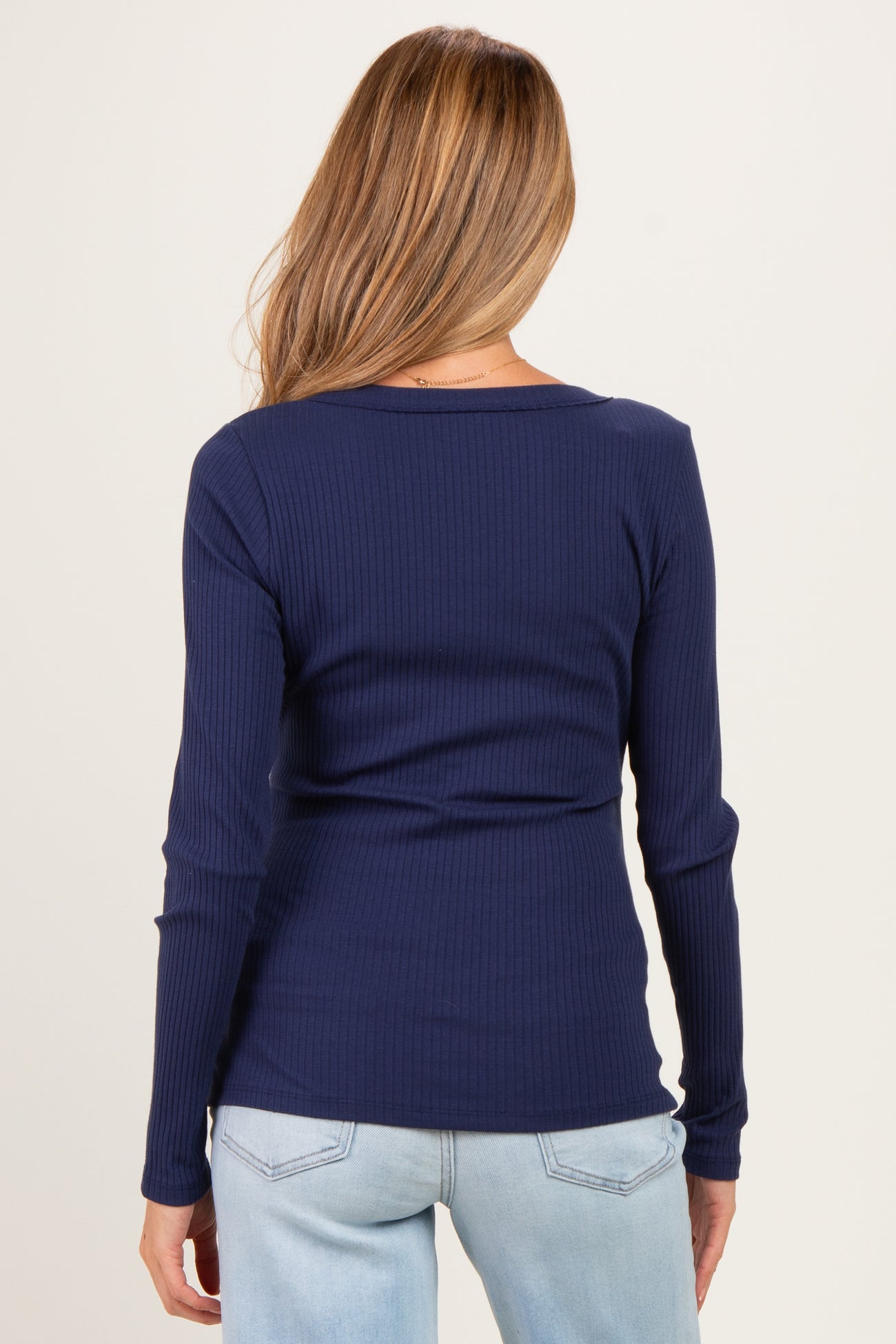 woman wearing a navy blue ribbed long sleeve maternity top, viewed from the back
