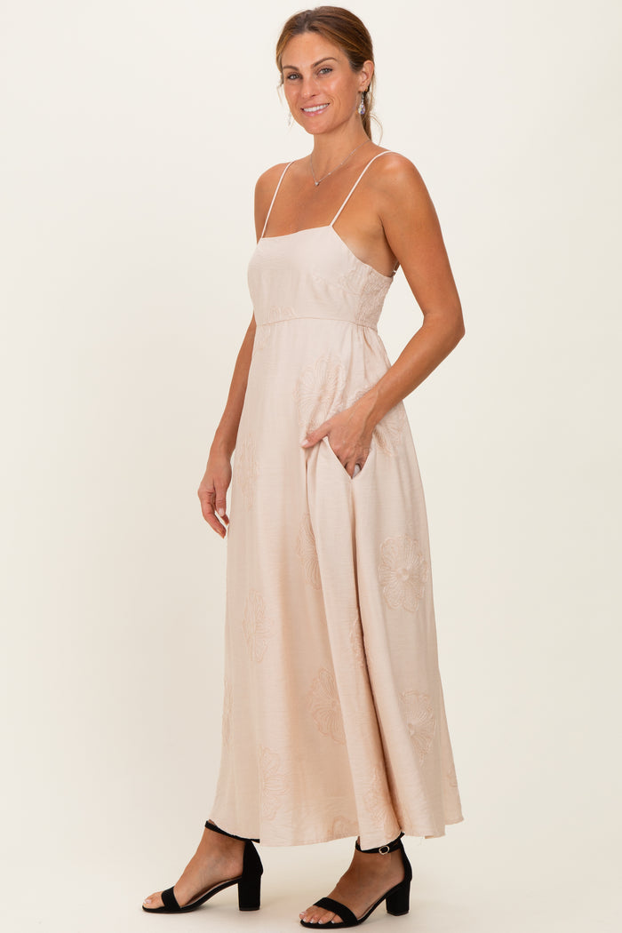 woman wearing a blush pink maxi dress with adjustable spaghetti straps and side pockets