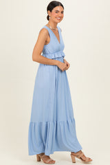 woman wearing a light blue sleeveless maxi dress with a tiered skirt and a fitted bodice, smiling in profile