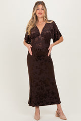 woman wearing a dark brown floral maternity maxi dress and gently holding her baby bump