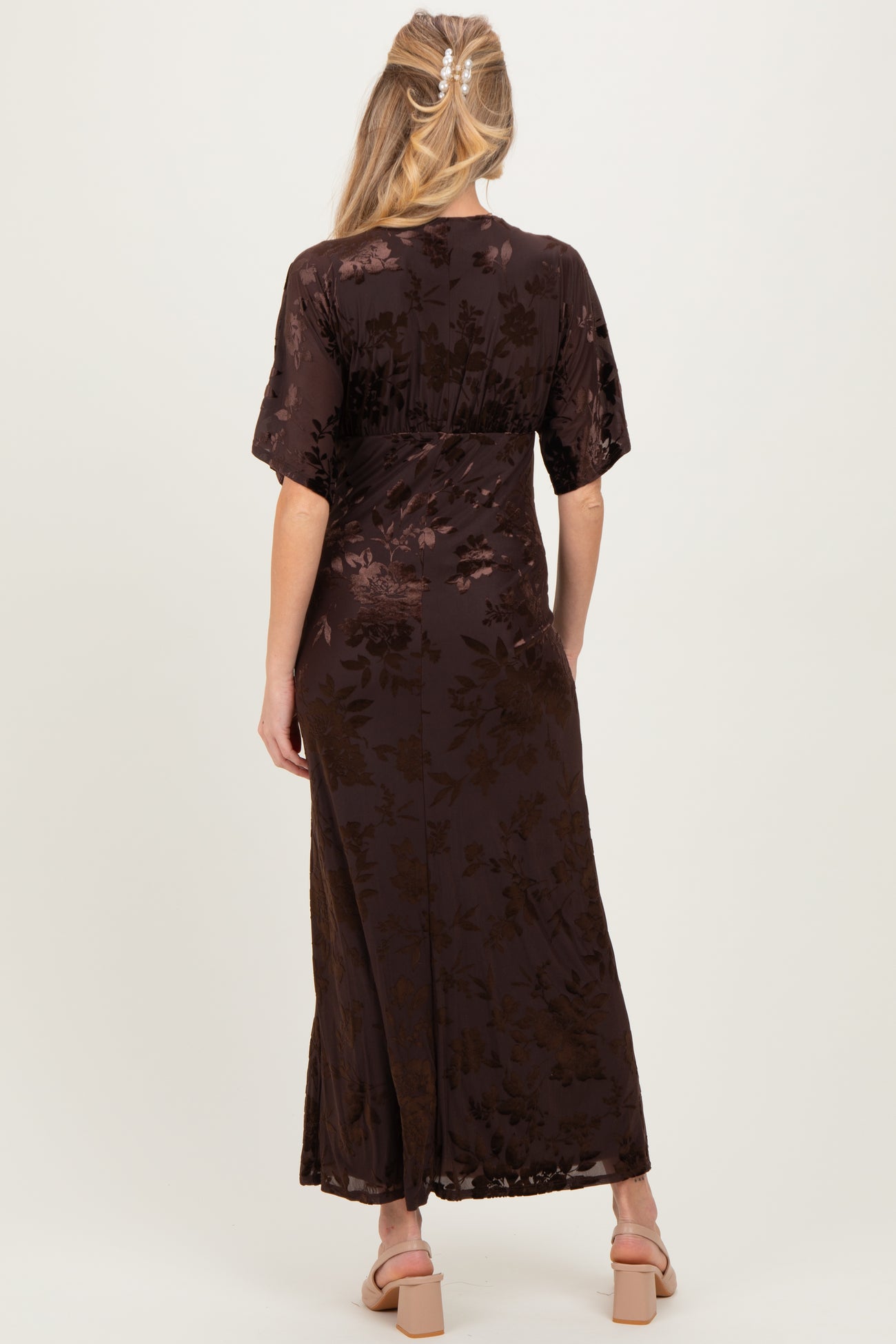 woman wearing a dark brown maternity dress with floral pattern and short sleeves, showing the back view