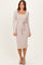 woman wearing a light taupe long sleeve ribbed dress with a square neckline and a tied waist detail