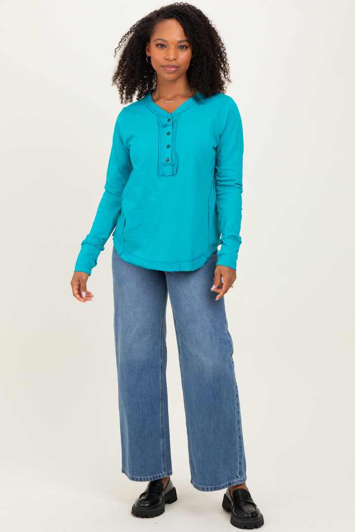 woman wearing a turquoise long sleeve henley top paired with wide leg jeans and black loafers