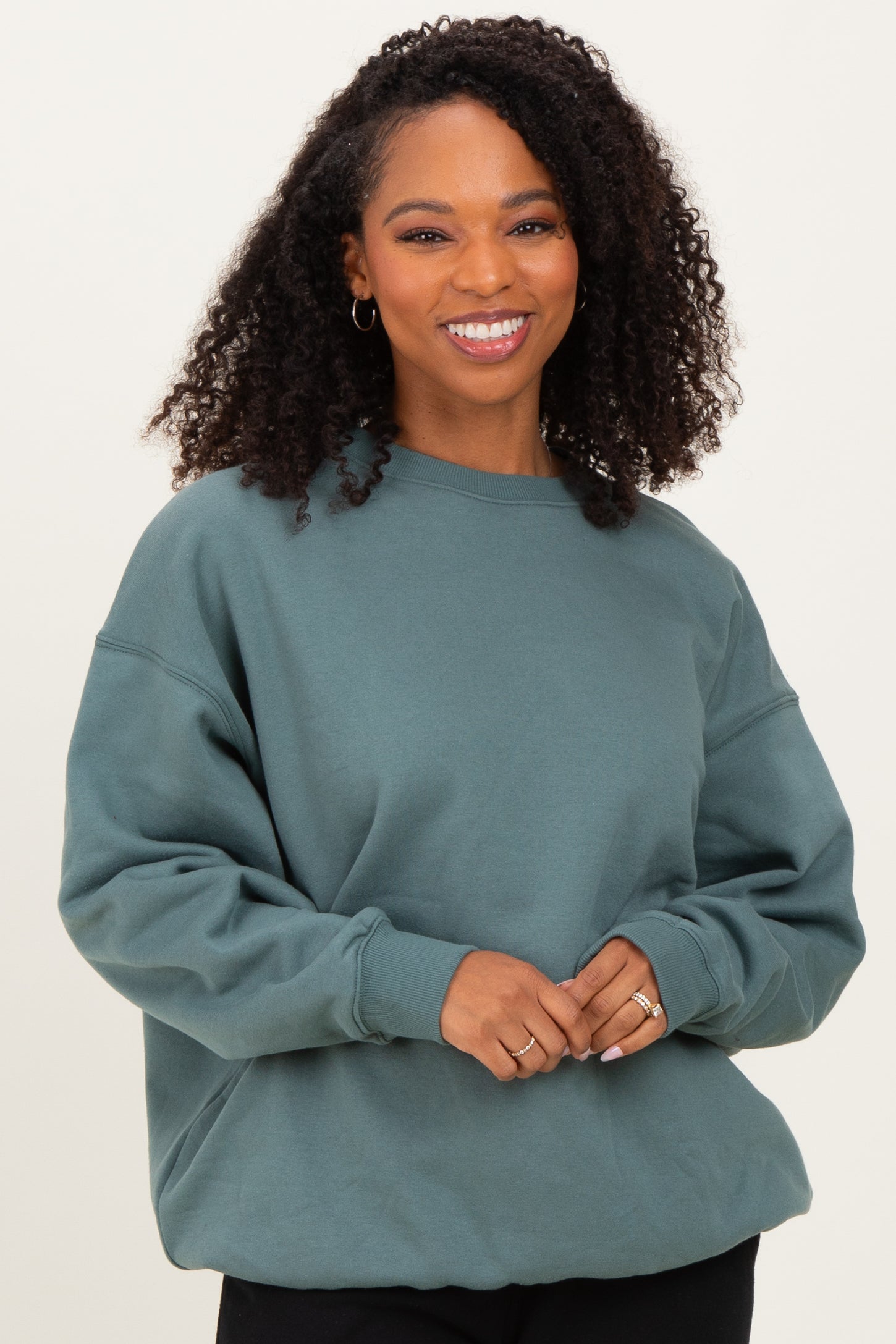 woman wearing a teal oversized sweatshirt with long sleeves and a crew neckline