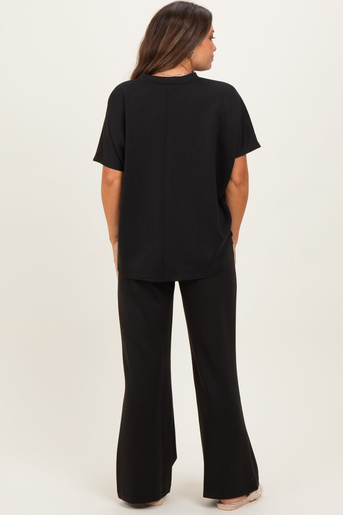woman wearing a black maternity top and matching flared maternity pants, view from the back