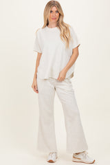 woman wearing a light grey relaxed fit top and matching wide leg pants with sneakers