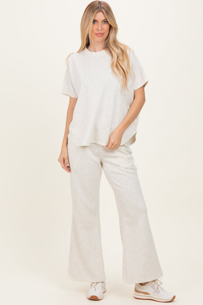 woman wearing a light grey relaxed fit top and matching wide leg pants with sneakers