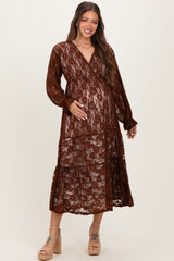 woman wearing a rust lace maternity dress with a tiered skirt and deep v-neck, holding her baby bump