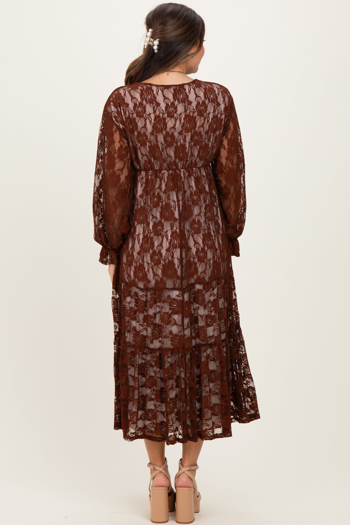 woman wearing a brown lace maternity dress with long sleeves and a flowing silhouette, shown from the back