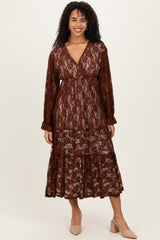woman wearing a brown lace midi dress with long sleeves and a tiered skirt, smiling at the camera