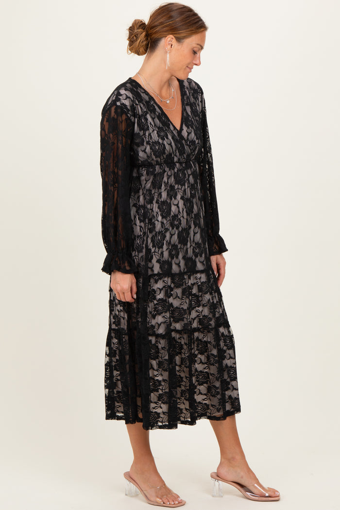 woman wearing a black lace midi dress with long sleeves and a layered skirt, styled with clear heeled sandals