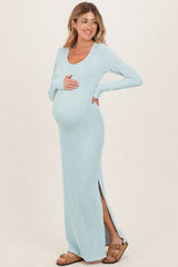 woman wearing a light blue ribbed maternity maxi dress with side slits and holding her baby bump