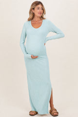 woman wearing a light blue ribbed maternity maxi dress with a side slit and holding her baby bump