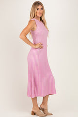 woman wearing a light pink ribbed sleeveless midi dress with a flared hem and styled with neutral slip-on shoes