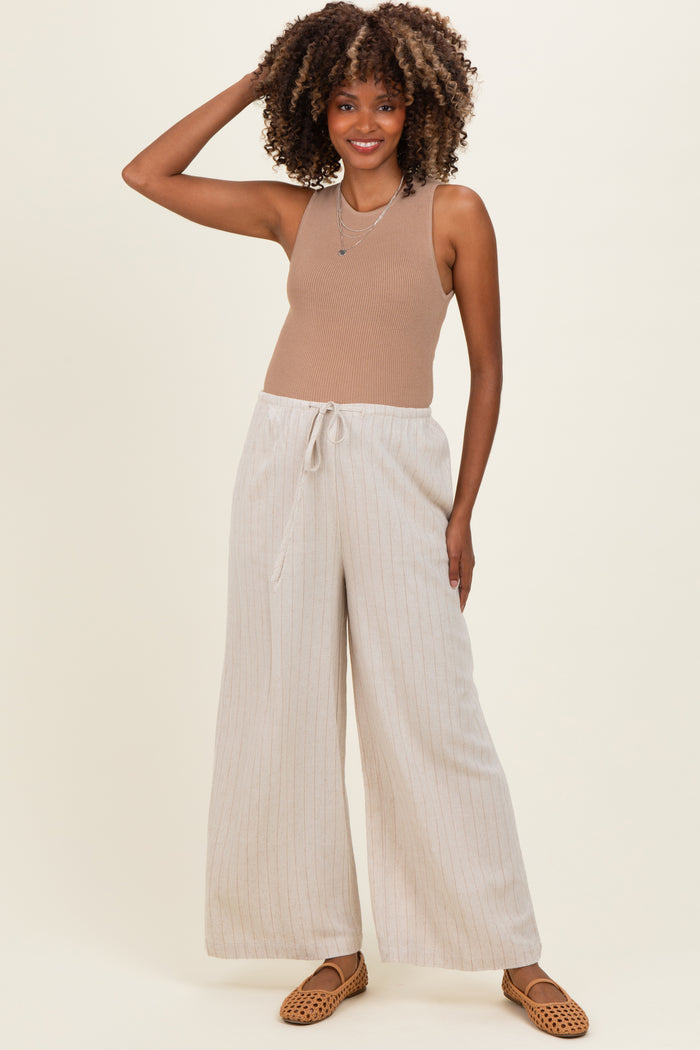 woman wearing a tan ribbed tank top and light striped maternity wide-leg pants with drawstring detail