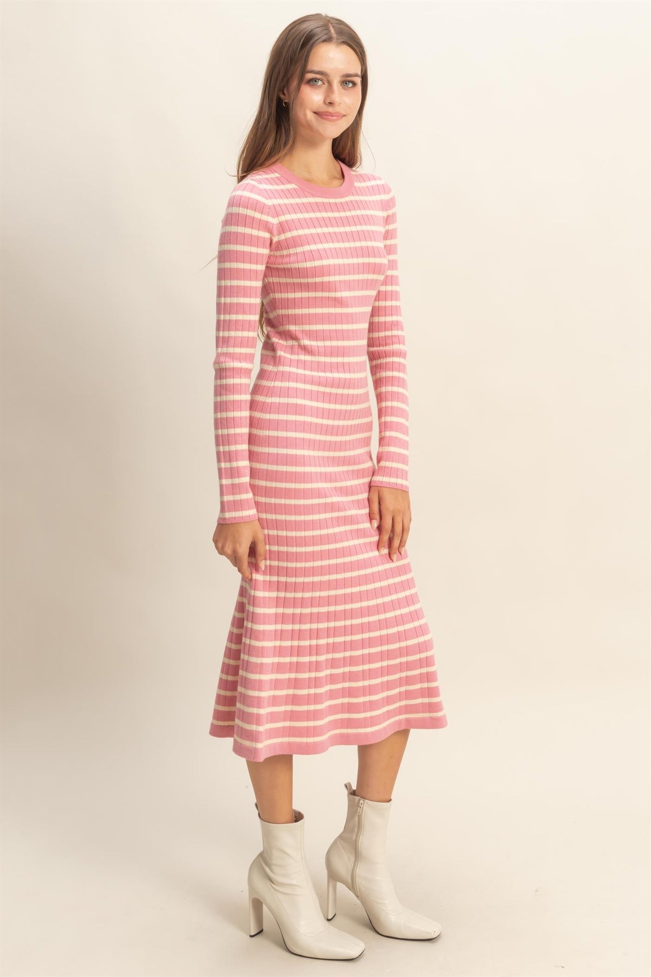 woman wearing a pink and white striped long sleeve fitted dress with a flared hem and ankle boots