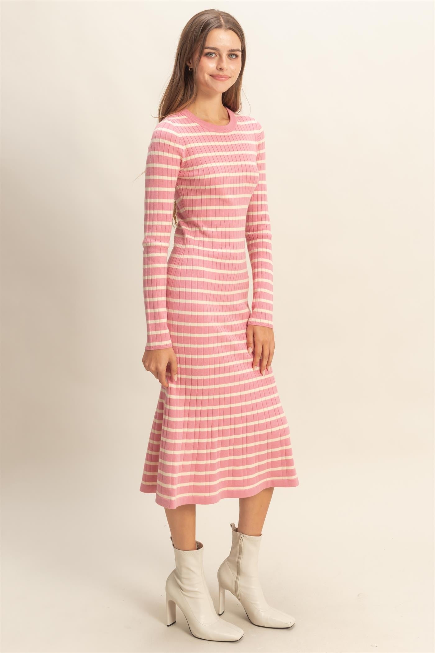 woman wearing a pink and white striped long sleeve fitted dress with a flared hem and ankle boots
